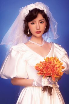 a woman in a white wedding dress holding a bouquet of flowers and wearing a veil