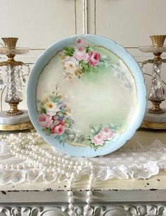 a plate sitting on top of a table next to two candles and a lace doily