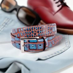 Crafted with impeccable attention to detail, the ZT52907 Italian Embossed Croc Indigo with Red belt exudes sophistication and elegance. Crafted with soft Italian calf leather in a rich chocolate hue, it has been stained with a teal technique for an unforgettable statement tone. Statement silver buckle and a 35mm or 1 7/16 width is the final nuance of this timeless accessory, perfect with any cool jeans. Designer Brown Belt For Formal Occasions, Luxury Fitted Belts With Belt Loops, Luxury Brown Belt For Business, Brown Luxury Formal Belt, Luxury Formal Belt With Leather Lining, Luxury Leather-lined Belt For Formal Occasions, Luxury Brown Belt For Formal Occasions, Luxury Blue Leather Belt, Luxury Red Leather Belt