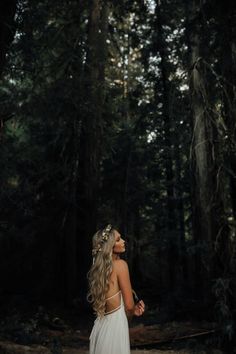 a woman in a white dress standing in the woods