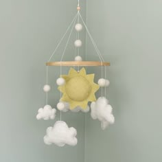 a yellow sun and clouds mobile hanging from the ceiling in a child's room