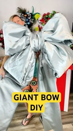 a woman is standing in front of a giant bow