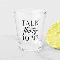 a shot glass with the words talk thirty to me next to a lemon