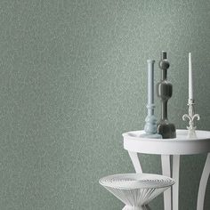 a white table with two candles on top of it next to a green wallpaper