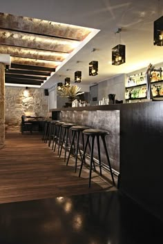 an empty bar with stools in front of it and lights hanging from the ceiling