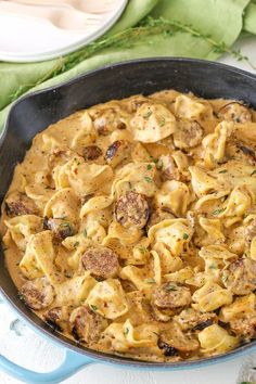 a skillet filled with pasta and meatballs on top of a white tablecloth