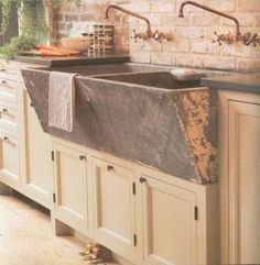 a kitchen sink sitting under a faucet next to a counter top and cabinets