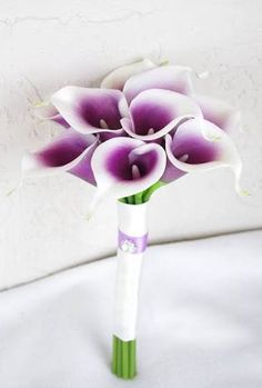 purple and white flowers in a vase on a bed