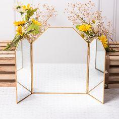 two mirrors with flowers in them sitting on a table