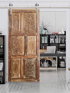 an open wooden door sitting inside of a living room next to a bookshelf