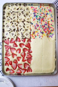 a pan filled with sliced up strawberries and chocolate chip cheesecakes covered in sprinkles