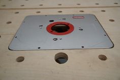 a metal plate with holes in the middle on a table top, surrounded by screws