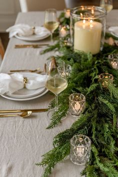 the table is set with candles and greenery