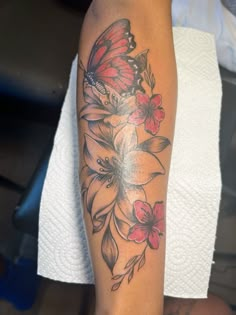 a woman's arm with flowers and a butterfly tattoo on the left side of her arm