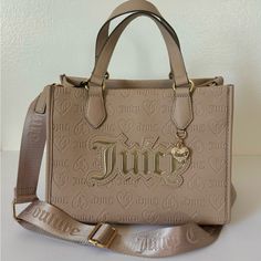 Juicy Couture Upgrade U Mini Tote Condition: New With Tags Color: Cafe * Tan / Cafe Faux Leather W/ Debossed Juicy Logos * Gold Tone Hardware And Front Heart Charm W/ Crystal Accents * Flat Double Carry Handles W/ 5” Drop * Adjustable Crossbody Strap W/ 23” Drop (Not Detachable) * Open Top W/ 1 Zip Pocket And 2 Slip Pockets * Measurements: 9.5”W X 7.75”H X 5.5”D Msrp $99.00 Cafe Gold, Juicy Couture Clothes, Juicy Bag, Candle Pedestal, Luxury Bags Collection, Juicy Couture Purse, Aesthetic Bags, Beige Bag, Girly Bags