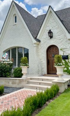 a white brick house with potted plants and steps leading to the front door is shown