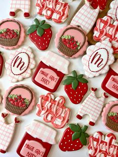 decorated cookies are arranged in the shape of strawberrys and picnic items on a table