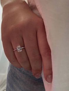 a close up of a person's hand wearing a diamond ring