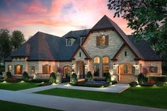 a large brick house with lots of windows and lights on it's front porch