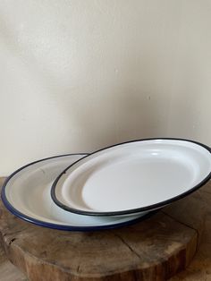 two white and blue plates sitting on top of a wooden table next to a wall