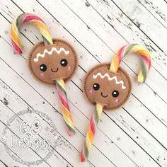 two gingerbread cookies with candy canes on a white wooden surface, one has a smiling face and the other has eyes