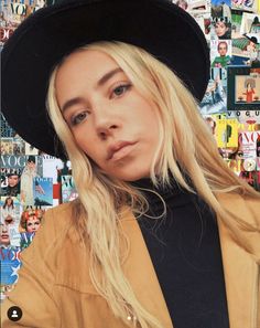 a woman with blonde hair wearing a black hat in front of a collage of comic books