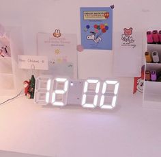 an alarm clock sitting on top of a white table next to a shelf with pens and markers