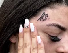 a close up of a person with a butterfly tattoo on their forehead and eyeliners