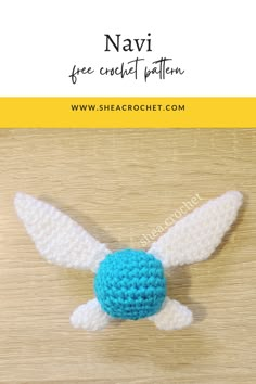 a crocheted blue and white bird with wings on top of a wooden table