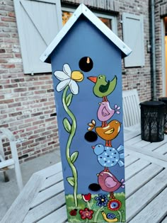 a painted birdhouse sitting on top of a wooden bench