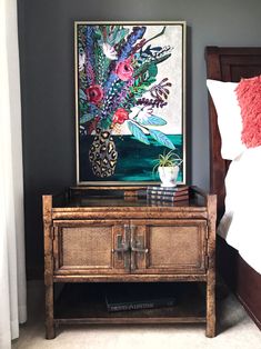 a painting on the wall next to a table with a vase and flowers in it