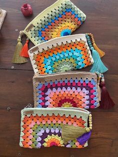 three crocheted bags with tassels on top of a wooden table next to an apple