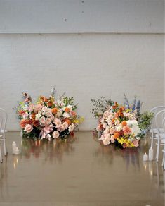 two white chairs with flowers on them and candles in front of the seats are set up for a wedding ceremony