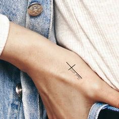 a woman's arm with a cross tattoo on the left side of her wrist