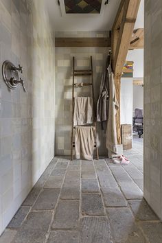 a ladder in a bathroom next to a towel rack with towels hanging on the wall