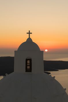 the sun is setting behind a small church with a cross on it's roof