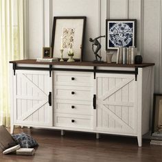 a white cabinet with sliding doors and pictures on it's top, sitting in a room