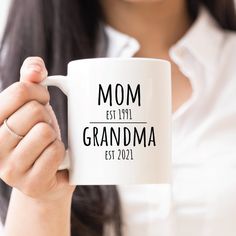 a woman holding a coffee mug with the words mom est 1971 grandma est 2021 on it