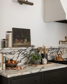 a kitchen with marble counter tops and brass accents on the wall above it is a potted plant