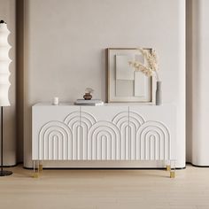 an art deco sideboard in white and gold with a mirror on the wall next to it