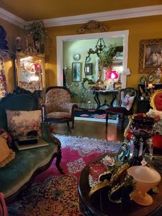 a living room filled with lots of furniture next to a wall covered in pictures and paintings