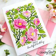 some pink flowers and green leaves are on top of two cards with the words happy birthday