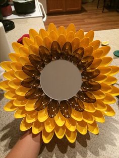 a sunflower is being held up by someone's hand on the counter top