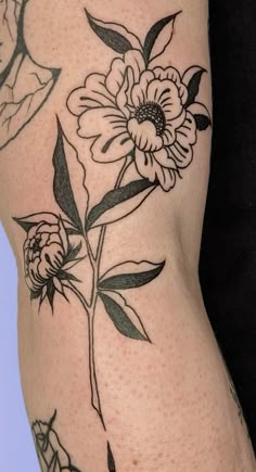 a woman's thigh with flowers on it and leaves around the thighs, as well as an arm tattoo