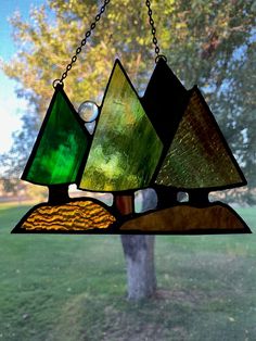 a stained glass lamp hanging from a chain on a window sill in front of a tree