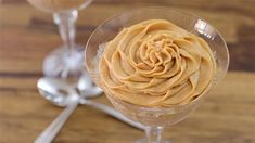 a dessert in a wine glass with a spoon next to it on a wooden table