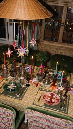 the table is set for christmas dinner with candles and plates on it, along with other holiday decorations