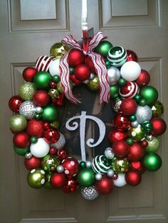 a christmas wreath with ornaments hanging on the front door and monogrammed letter p