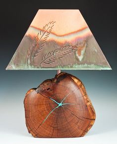 a wooden table lamp with a glass shade on it's base and a tree stump as the base