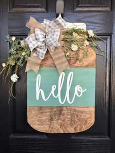 a wooden door hanger with the word hello painted on it and a bow tie